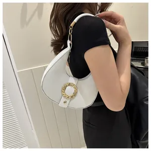 Close-up of a white crescent shoulder bag featuring a golden spiral buckle and litchi texture