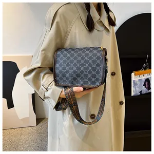 Détail du sac bandoulière rétro avec sangle ethnique sur un trench-coat beige élégant