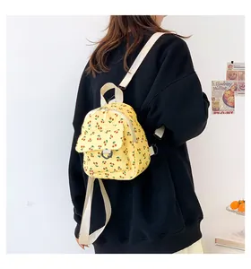 Mini yellow corduroy backpack with red cherry print shown from a side-angle on model