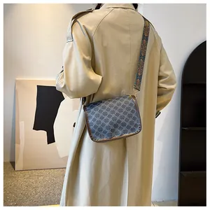 Détail d'un sac bandoulière vintage aux motifs floraux et large sangle tissée ethnique