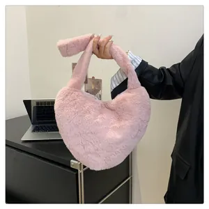 Gros plan du sac à main en fausse fourrure rose en forme de cœur à texture pelucheuse