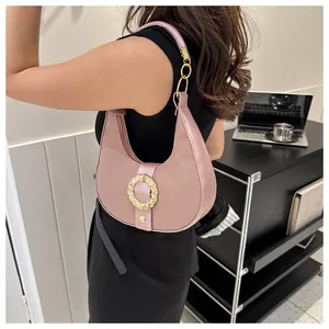 Detail of a dusty pink crescent underarm bag with gold ripple buckle shown on a model
