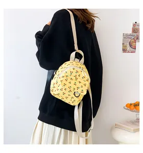 Close-up of yellow corduroy mini backpack with cherry print on a person's back
