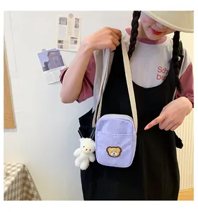 Detail of light purple corduroy crossbody bag featuring a cute brown bear patch and white charm