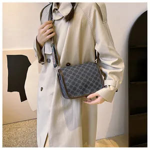 Détail du sac bandoulière vintage avec large sangle bohème brodée sur manteau beige