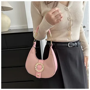 Pink crescent underarm bag with gold twisted buckle shown held by a female model