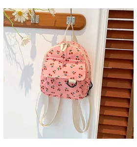Pink corduroy mini backpack with cherry print hanging on a hook for daily leisure