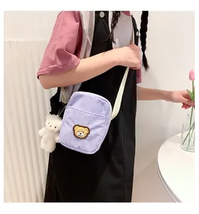 Detail of light purple corduroy crossbody bag with cute bear embroidery and plush charm