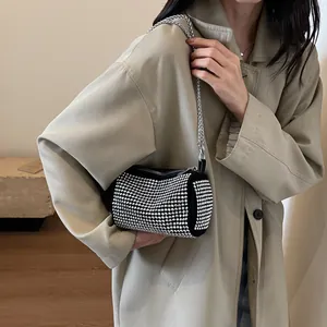 Elegante borsa a cilindro nera con strass e catena argentata, indossata da una modella