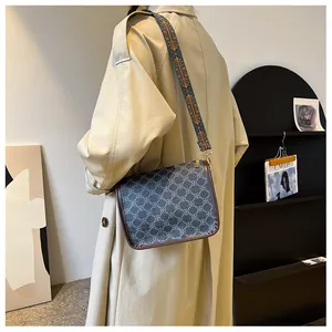 Détail d'un sac bandoulière à motifs avec large sangle florale porté par un mannequin
