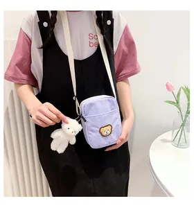 Detail of light purple corduroy bear crossbody bag with plush charm on a model