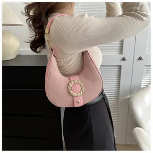 Pink hobo shoulder bag with golden ring buckle detail worn by model in minimalist setting