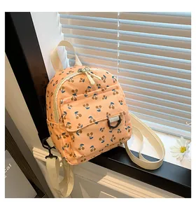 Detailed view of pink corduroy mini backpack with cherry print and adjustable straps