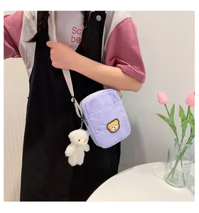 Detail of purple corduroy crossbody bag featuring a cute bear patch and plush charm