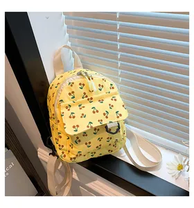 Detail view of yellow corduroy mini backpack with red cherry print and adjustable straps