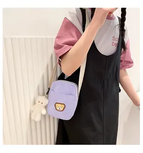Detail of light purple corduroy crossbody bag with cartoon bear patch and plush charm