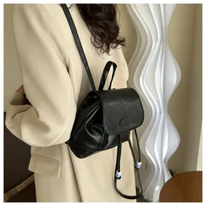 Vue latérale d'un mini sac à dos en similicuir noir avec détails de perles et cordon