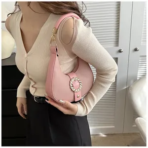 Detail view of pink leather underarm bag featuring a textured finish and golden buckle