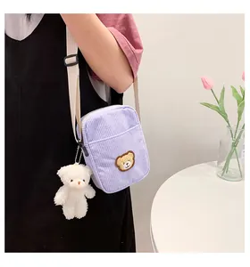 Detail of purple corduroy bear crossbody bag with plush charm and adjustable strap