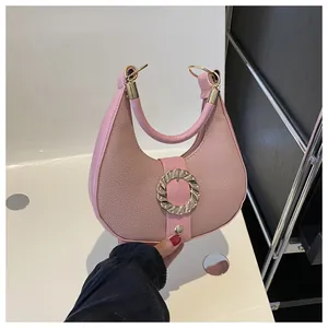 Close-up of pink crescent handbag with lychee leather texture and golden metal buckle