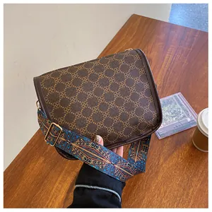 Détail du sac vintage en cuir marron avec motif floral et bandoulière géométrique