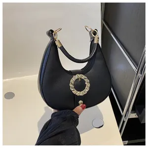 Close-up of black hobo bag with litchi texture leather and golden wave metal buckle