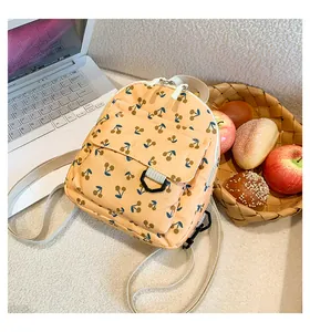 Detail view of corduroy mini backpack with cherry print on a white fuzzy rug