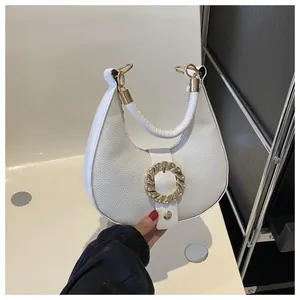 Detail of white half-moon handbag featuring lychee texture and gold circular buckle