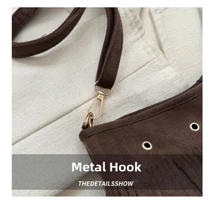 Detail of dark brown suede bag with golden metal hook and stylish fringe accents