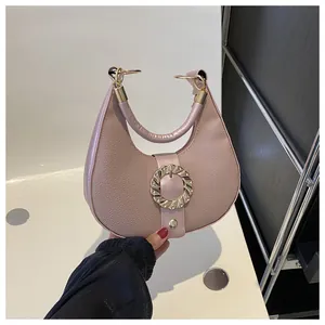 Detail of mauve crescent bag with lychee texture and large golden metal buckle