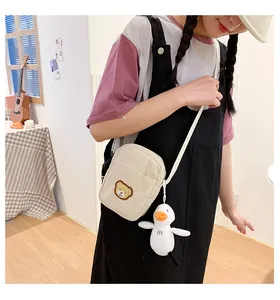 Detail of cream corduroy crossbody bag with a cute white duck plush charm pendant