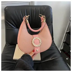 Detail of pink lychee leather moon bag with golden wave buckle and magnetic closure