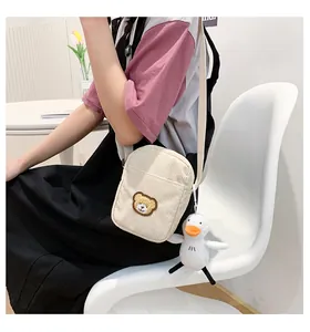 Detail of corduroy crossbody bag with cute bear patch and plush duckling charm