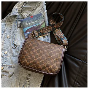 Détail d'un sac bandoulière marron à motifs avec large sangle en tissu ethnique