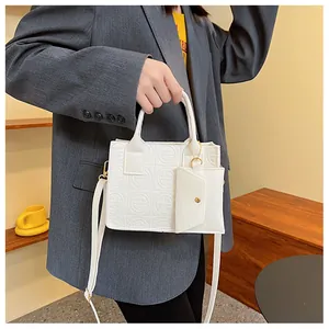 Detailed view of white embossed felt crossbody bag with mini pouch and gold hardware