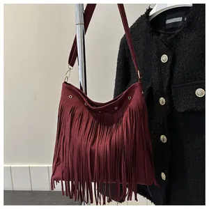 Detailed view of burgundy bohemian tassel shoulder bag with metallic ring and suede texture