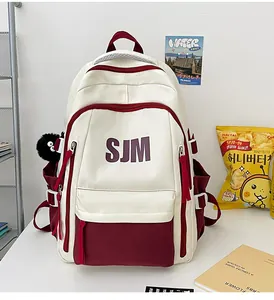 Detalle macro de mochila roja y blanca con logo SJM y colgante de peluche en un escritorio