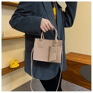 Detail of beige embossed handbag with matching mini pouch accessory on a blazer outfit