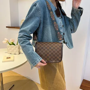 Sac bandoulière marron vintage avec large sangle brodée ethnique dans une pièce épurée