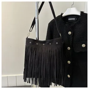 Close-up of black fringe shoulder bag featuring bohemian tassels and gold metal hardware
