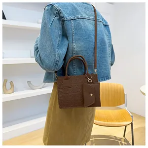 Detail of brown embossed felt handbag with matching mini pouch on a female model