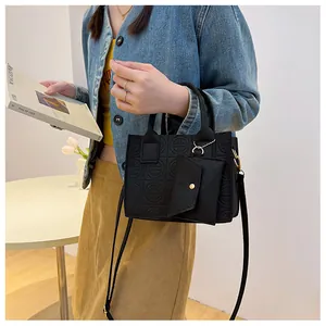 Detail of black embossed felt tote bag with matching mini pouch on a stylish model