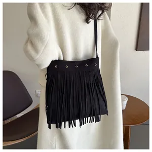 Detailed view of bohemian black fringe crossbody bag with gold grommets on wool coat