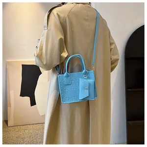 Light blue quilted handbag and small pouch shown on model in a modern interior setting