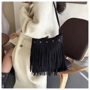 Detail of bohemian black suede fringe bag with metallic eyelet buckles on a stylish model