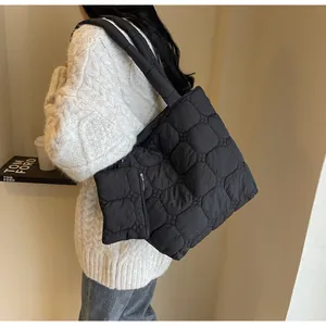 Dettaglio della borsa tote trapuntata nera con astuccio abbinato e sfondo minimalista