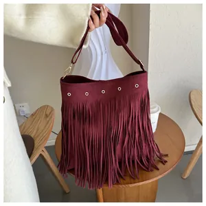Close-up of deep red suede bohemian fringe bag with gold eyelets and soft tassels