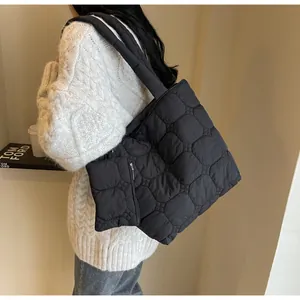 Dettaglio di una borsa tote trapuntata nera con tracolla larga e morbida imbottitura
