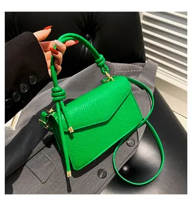 Dettaglio della borsa verde in pelle martellata con hardware dorato e manico con nodo