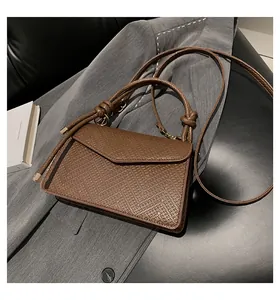 Dettaglio borsa in pelle martellata marrone con nodo e finiture in metallo
